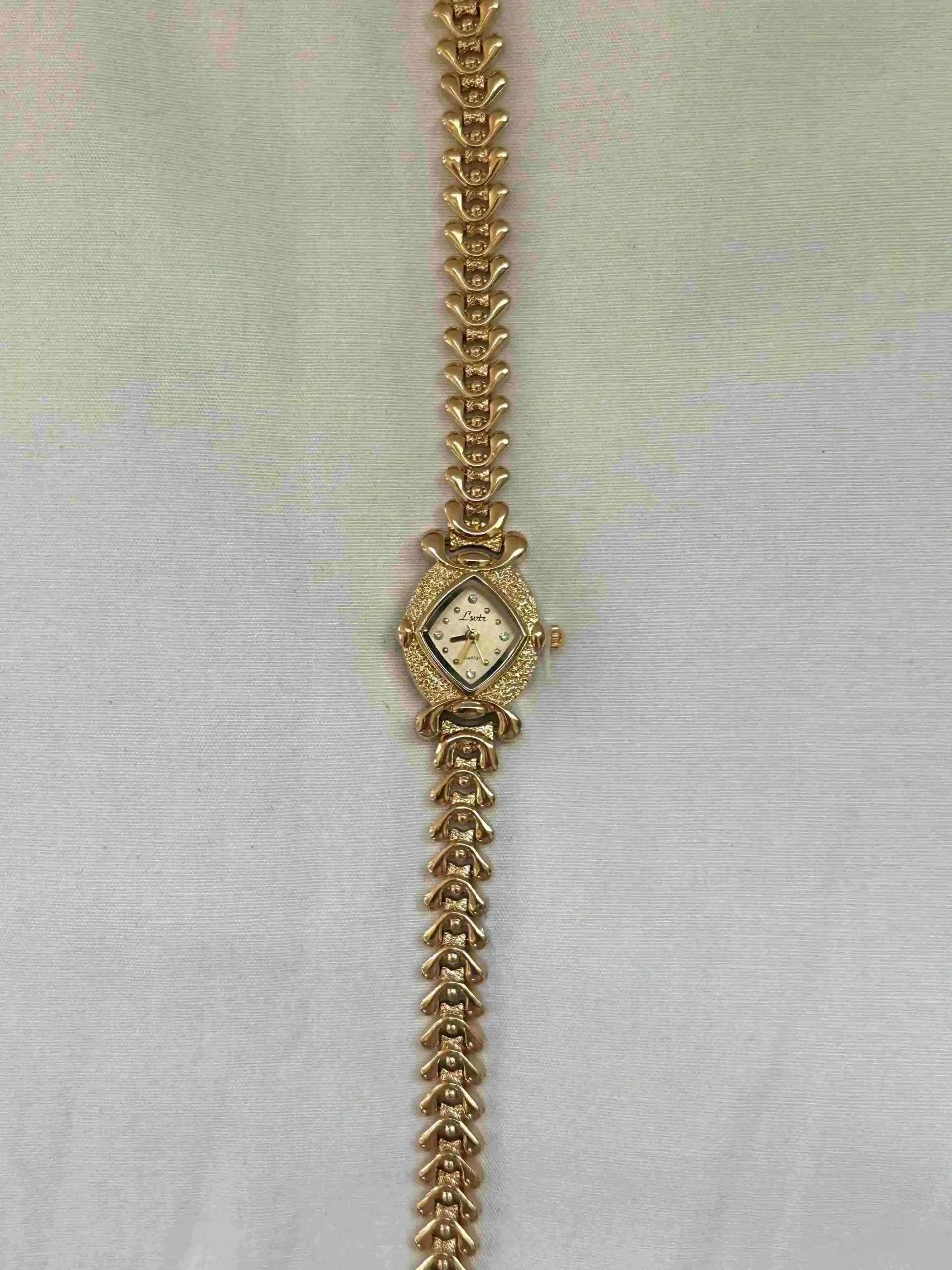 paslanmaz çelik kadın saati Karo desenli gold paslanmaz çelik kadın kol saati, beyaz iç yüzeyli, şık ve vintage tasarım.